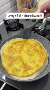 Using a spatula to press the tortilla onto the eggs to ensure they stick together perfectly.