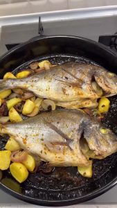 Removing the protective wet parchment paper from the fish after the initial 40 minutes of roasting.