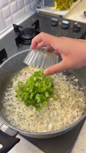 Sautéing diced onions and green peppers in melted butter in a shallow pilaf pot.