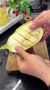 Scoring the flesh of halved globe eggplants in a diamond pattern before roasting.