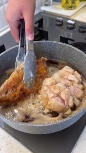 Frying flour-dusted chicken fillets in a skillet with melted butter until golden brown and crispy.