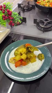 Spreading creamy garlic yogurt on a plate and topping it with hot, roasted spiced winter vegetables.