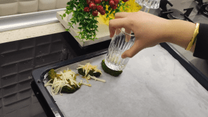 Using the flat bottom of a drinking glass to gently press down and smash the boiled broccoli florets.
