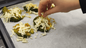 Generously topping the seasoned smashed broccoli with grated Kashar or mozzarella cheese.