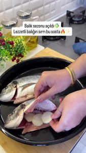 Placing fresh onion rings inside the sea bream to keep the fish moist and aromatic.