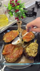 Filling the roasted eggplant boats with the mashed garlic tomato mixture.