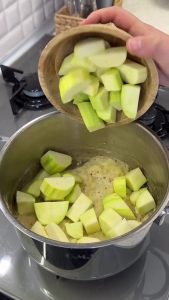 Adding fresh diced zucchini to the pot and stirring them with the onion and flour mixture.