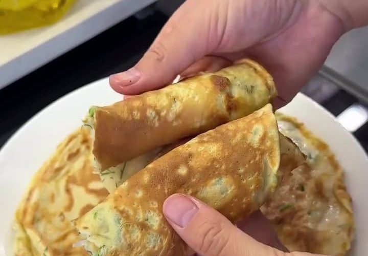 A stack of traditional Black Sea Kaygana pancakes garnished with fresh herbs and served with Turkish tea.
