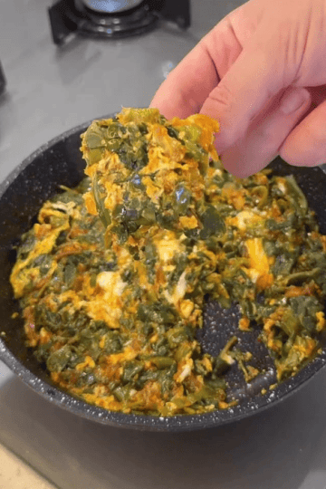 A healthy skillet of sautéed purslane and peppers topped with a cooked egg.