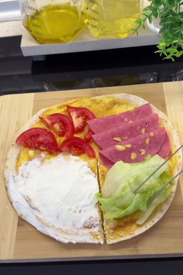 A crispy, toasted 5-minute breakfast wrap folded into a triangle with labneh, salami, and tomatoes.