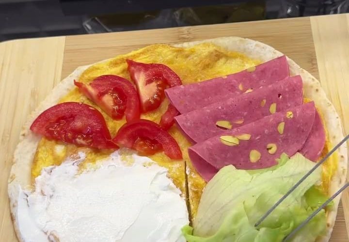 A crispy, toasted 5-minute breakfast wrap folded into a triangle with labneh, salami, and tomatoes.