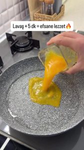 Pouring whisked eggs into a heated non-stick pan for a quick breakfast wrap.