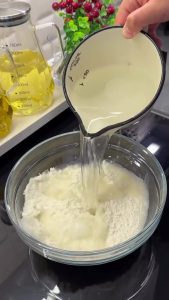 Whisking flour, water, and salt in a bowl to create a smooth liquid batter for no-knead flatbread.