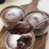 A warm chocolate soufflé with a molten center being opened with a spoon.