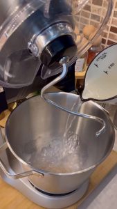 Mixing active dry yeast and sugar in warm water to begin the pizza dough.