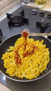 Adding a tablespoon of butter to the hot and creamy milk-simmered sweet corn.