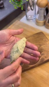 Placing a teaspoon of crumbled feta cheese in the center of the flattened dough.