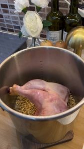 Placing soaked wheat and chicken thighs into a stainless steel pressure cooker.
