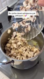 Adding finely chopped fresh mushrooms and garlic to the sautéed onions in the pot.