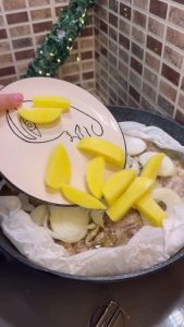 Adding cubed potatoes and sliced onions to the pan with the steaming chicken.