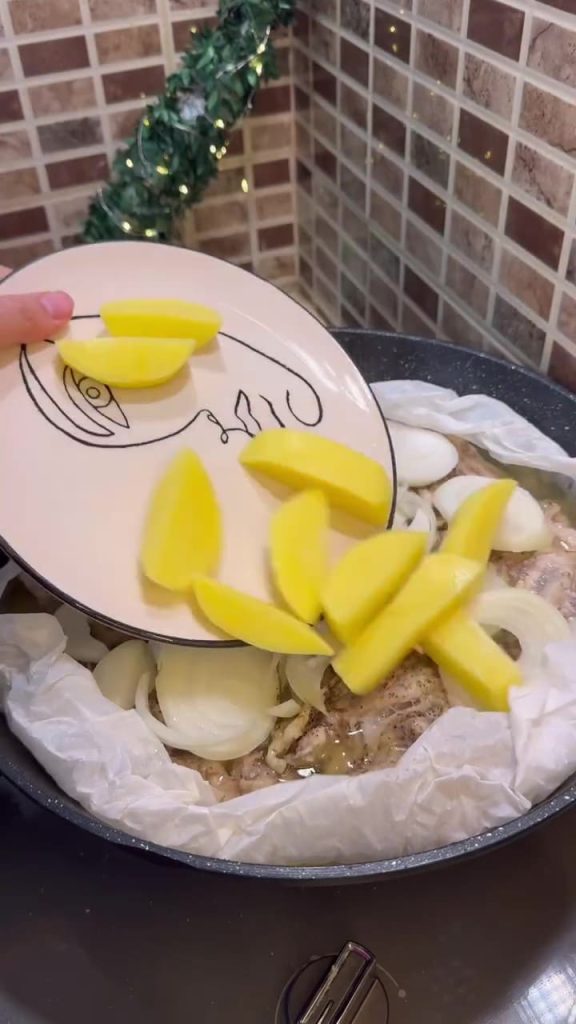 Adding cubed potatoes and sliced onions to the pan with the steaming chicken.