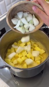 Adding diced potatoes and roughly chopped onions to the toasted cornmeal roux.