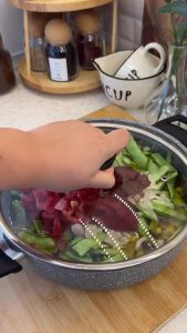 Adding cubed potatoes to the nearly cooked green beans for the final simmering stage.