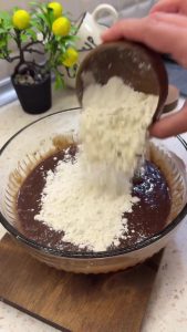 Adding all-purpose flour to the smooth chocolate and egg mixture.
