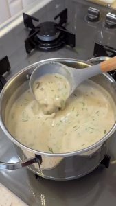 Stirring finely chopped fresh dill into the finished creamy mushroom soup for the final touch.