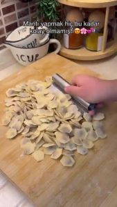 Spooning thick garlic yogurt over a plate of freshly boiled Turkish mantı.