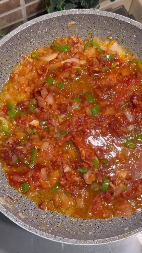 Adding fresh grated tomatoes to the sautéed onions and peppers.