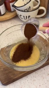 Adding instant coffee granules and hot boiling water to the whipped honey base.