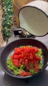 Adding fresh peeled and chopped tomatoes to sautéed peppers.