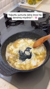 Adding fresh plain yogurt into the pan with melted butter to begin sautéing.