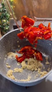 Adding chopped roasted peppers and minced garlic to the flour mixture.