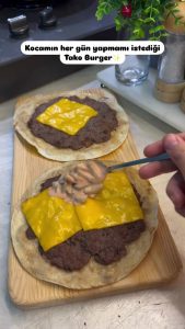 Adding homemade burger sauce, shredded lettuce, and diced onions to the taco.