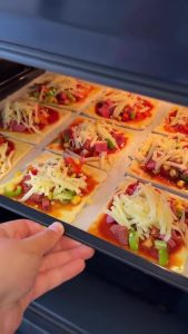 Topping the mini puff pastry pizzas with a generous layer of shredded kashar cheese.