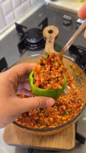 Adding dried mint, paprika, and a little water to the raw rice and meat filling mixture.