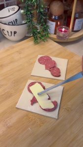 Placing sliced Turkish sucuk and kashar cheese on the puff pastry.