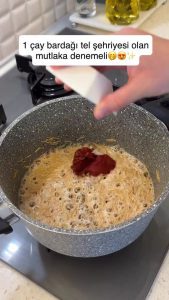 Stirring tomato and red pepper paste into the toasted vermicelli mixture.