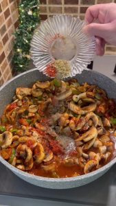 Adding red pepper flakes, oregano, and water to the mushroom sauté.