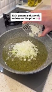 Adding washed and drained rice to the sautéed onions in a shallow pan.