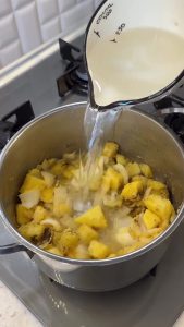 Pouring water and adding black pepper to the sautéed potato and cornmeal base.