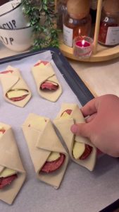 Placing the folded sucuk bites on a baking sheet with parchment paper.