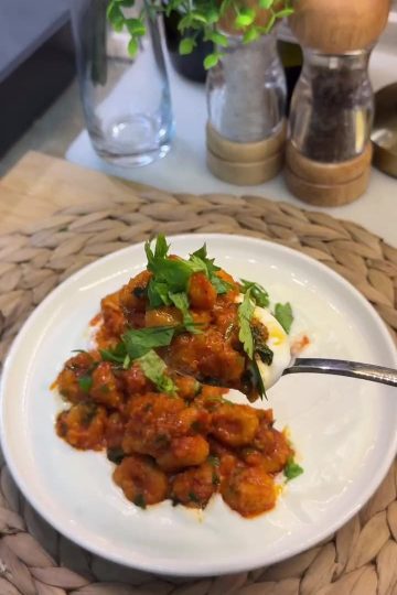 A platter of Turkish Fellah Köftesi meatballs in tomato sauce served over garlic yogurt.