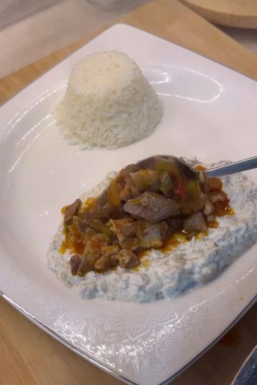 A plate of Alinazik Kebab featuring tender lamb cubes over smoky roasted eggplant and garlic yogurt puree.
