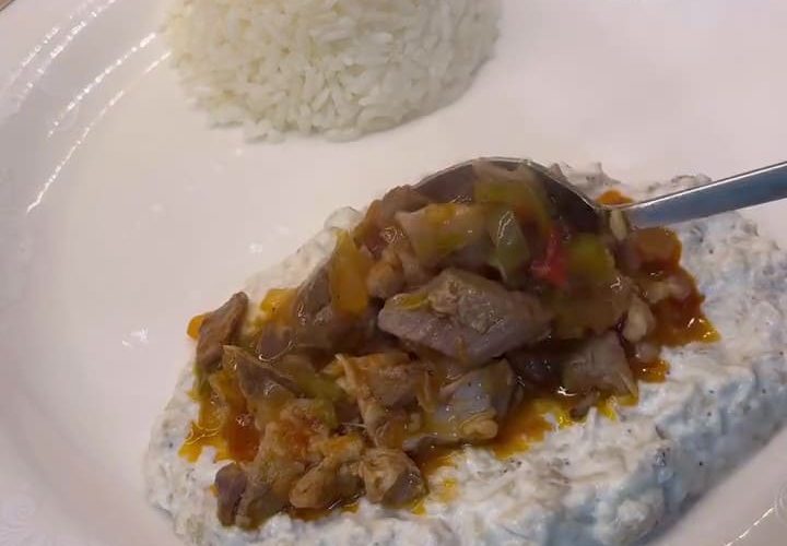A plate of Alinazik Kebab featuring tender lamb cubes over smoky roasted eggplant and garlic yogurt puree.