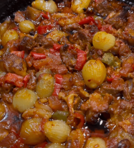 A traditional Turkish Belen Tava with roasted lamb, shallots, and peppers in a clay dish.