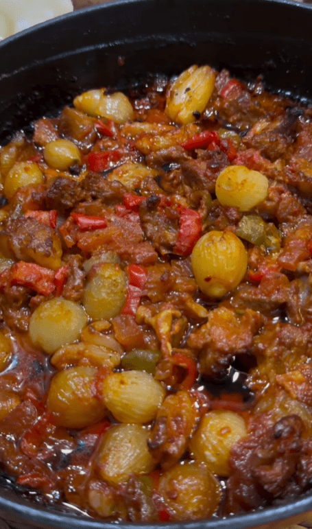 A traditional Turkish Belen Tava with roasted lamb, shallots, and peppers in a clay dish.