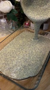 A freshly baked golden-brown poppy seed semolina cake in a glass baking dish.